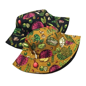Double-sided bucket hat featuring vegetable print in black and ginger yellow colors