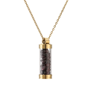 Close-up of golden necklace with glass perfume vial pendant filled with dark red stones