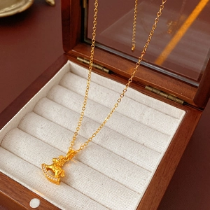 Close-up of gold plated horse pendant with sparkling diamonds on beige velvet cushion
