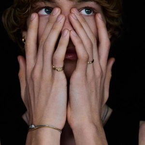Photo artistique de bagues dorées et d'un bracelet bicolore sur les mains du mannequin