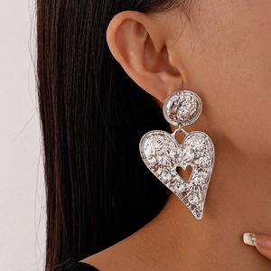 Detail of silver heart earrings with sparkling crystals and vintage hammered metal texture