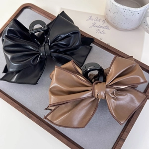 Close-up of vintage leather striped bow hair claws in black and brown on a tray