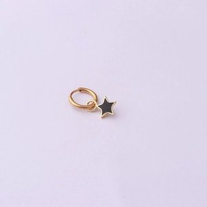Detail view of a gold-plated hoop earring featuring a sleek black star pendant accessory