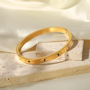Detalle de un brazalete de acero dorado con ojo turco y piedras de circonita de colores