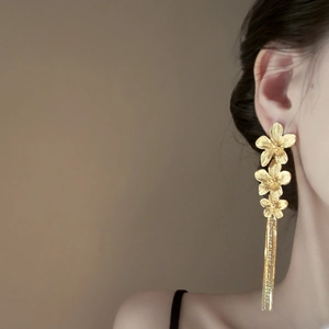 Elegant gold flower tassel earrings with crystal studs shown on model for length perspective