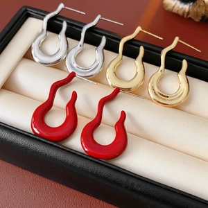 Macro view of U-shaped gourd stud earrings in gold and silver finish with enamel detail