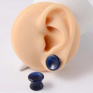 Macro detail of dark blue natural stone saddle ear gauges on a realistic ear model