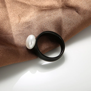 Detailed close-up of a French minimalist black ceramic ring with an elegant white pearl