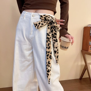 Dettaglio della cintura foulard in seta leopardata su pantaloni bianchi larghi