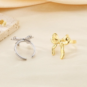 Detail of silver and gold bow rings with ribbon texture on a minimalist background