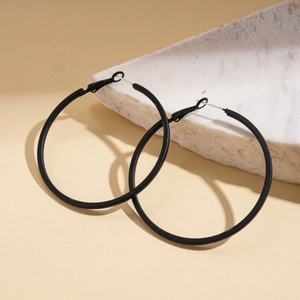 Minimalist large geometric black leather circle hoop earrings on white marble display stand