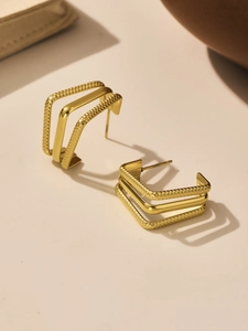 Detail of gold geometric square earrings featuring textured lattice and polished finish