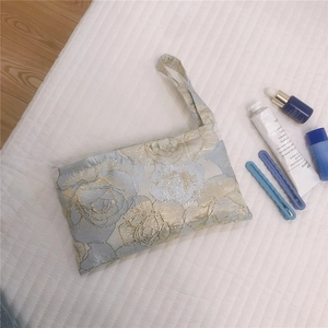 Detail of light blue floral jacquard phone bag with golden rose embroidery and handle