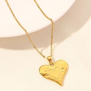 Detailed view of heart-shaped gold pendant necklace with starburst texture on ivory base