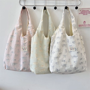 Detailed view of three canvas tote bags with cat illustrations hanging on a wall