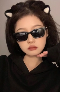 Front view of retro black narrow frame sunglasses worn by a female model for size scale