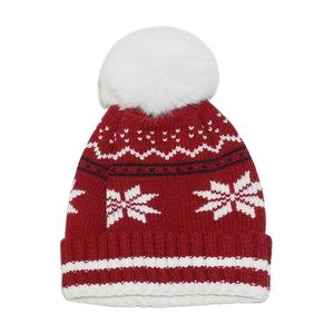 Close-up of red knit winter beanie featuring white snowflakes and a faux fur pompom