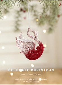 Close-up of elegant red flocked swan Christmas ornament with glitter detail on pine tree