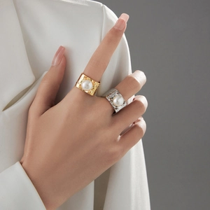 Detail of square gold pearl ring with hammered texture on woman's finger