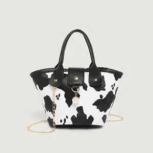 Mini cow print bucket bag with pearl pendant, black leather handle and gold chain strap