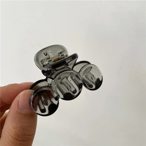Detailed view of a small greyish-black translucent hair claw clip held by a hand