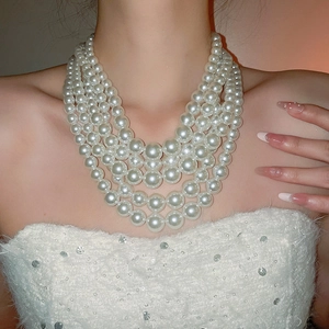 Detail of multi-layer pearl necklace on model wearing a white sequin dress