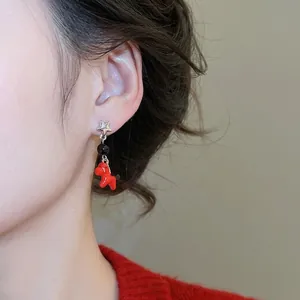 Silver needle horse and star earrings worn by a model in a cozy red sweater outfit
