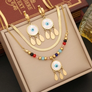 Gold stainless steel double-layered necklace and evil eye earring set on a beige jewelry box