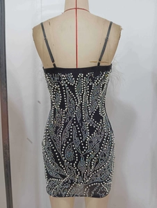 Détails de robe de luxe avec perles blanches, strass colorés et accents de plumes