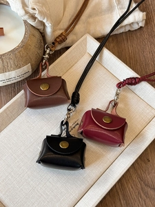 Detailed view of mini leather earphone pouches in brown, black and red with metal buttons