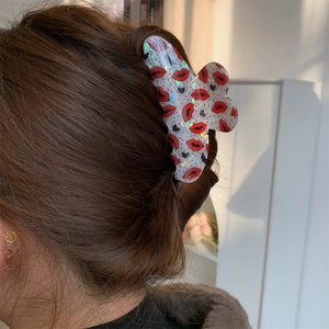 Detail view of heart and red lip print hair claw clip with holographic finish on hair