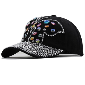 Détails de strass colorés et motif papillon sur cette casquette en jean noir délavé