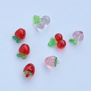Acrylic fruit charms like strawberry and cherry for DIY jewelry on blue background
