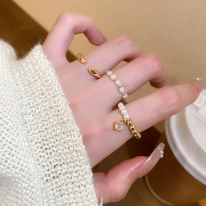 Detailed view of a 3-piece gold-plated ring set with pearls and zircon on a model's hand