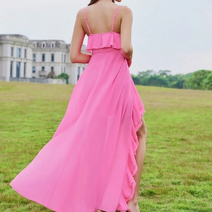 Detail of a bright pink chiffon maxi dress featuring an open back and ruffled high-low hemline
