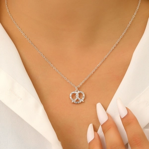 Primo piano di una collana con ciondolo a pretzel in argento e zirconi su una modella
