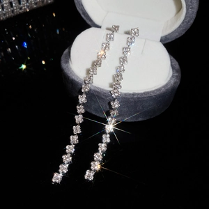 Macro shot of silver tassel earrings with sparkling rhinestones in a velvet jewelry box