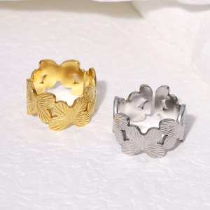 Dettaglio degli anelli a farfalla oro e argento con trama metallica incisa