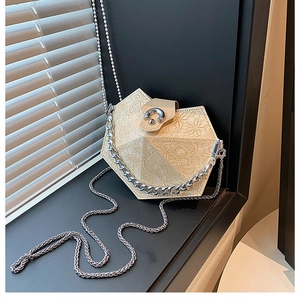 Detail of beige geometric handbag with delicate lace texture and silver chain strap