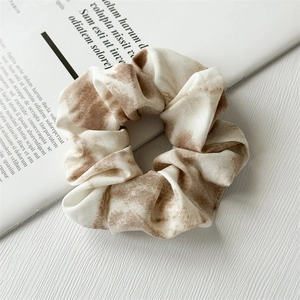 Detail of brown tie-dye chiffon scrunchie with soft fabric folds on a book background
