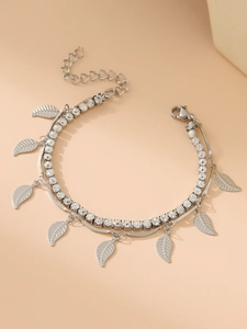 Macro detail of silver double-layer bracelet featuring leaf charms and crystal tennis chain