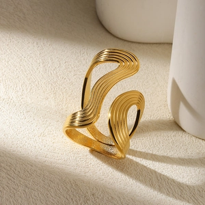 Detailed close-up of golden irregular wavy layered ring on a textured background