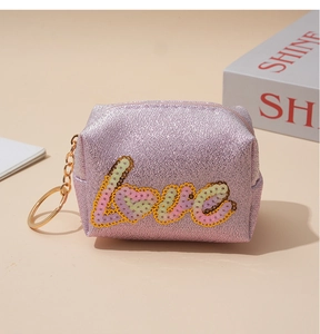 Detail of pink glitter coin purse with colorful LOVE sequin embroidery and gold keychain