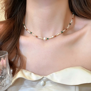 Detail of beaded necklace with pearls, beige tubes, and colorful beads on a model