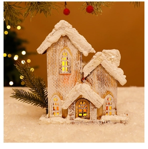 Close-up of glowing wooden Christmas house with warm LED lights and artificial snow