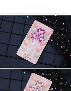 Pink metallic star and heart birthday candles with support sticks on a decorative card