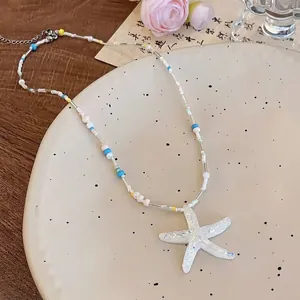 Détail d'un collier de perles avec pendentif étoile de mer sur une assiette en céramique