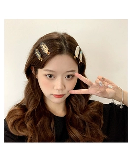 Detailed view of acetate hair clips in amber and pearlescent white on female model