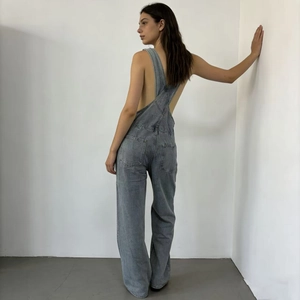 Detailed back view of loose denim overalls featuring cross straps and large pockets