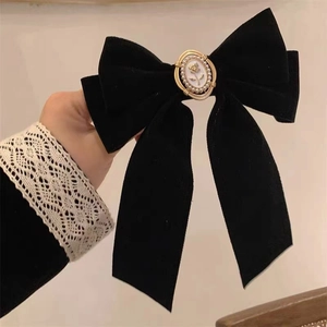 Elegant black velvet bow hair clip with rose relief and pearl detail held by model